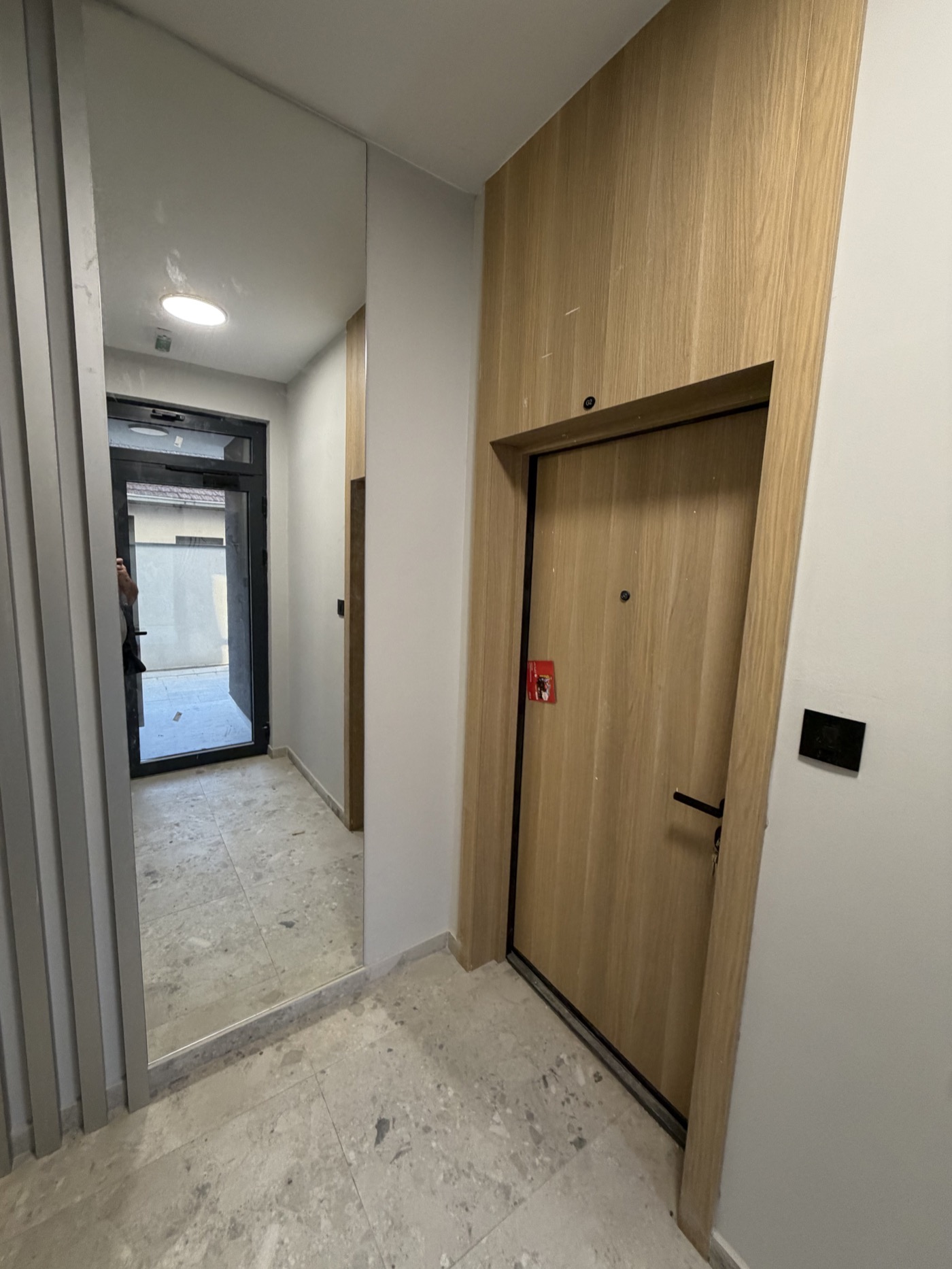 Zajednički hodnik sa drvenim oblogama i svetlim kamenim pločicama
